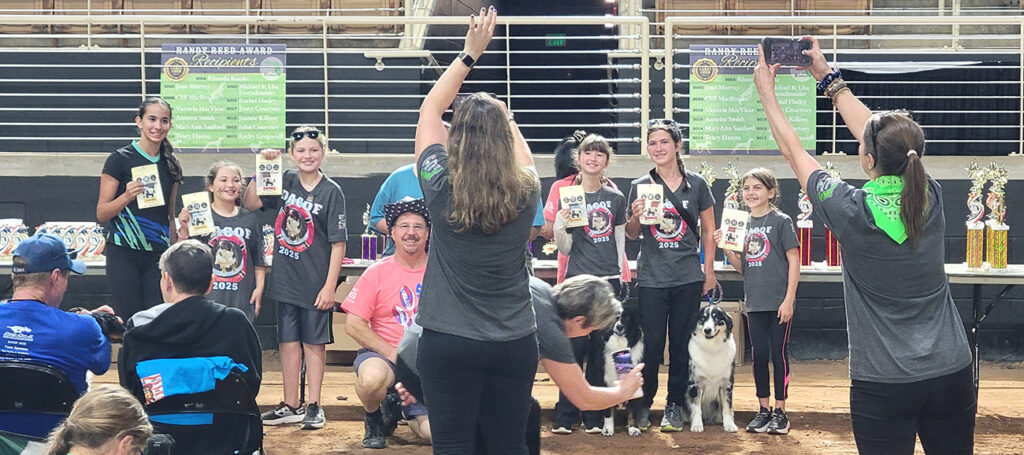 Kids lined up to have their photo taken in a horse arena